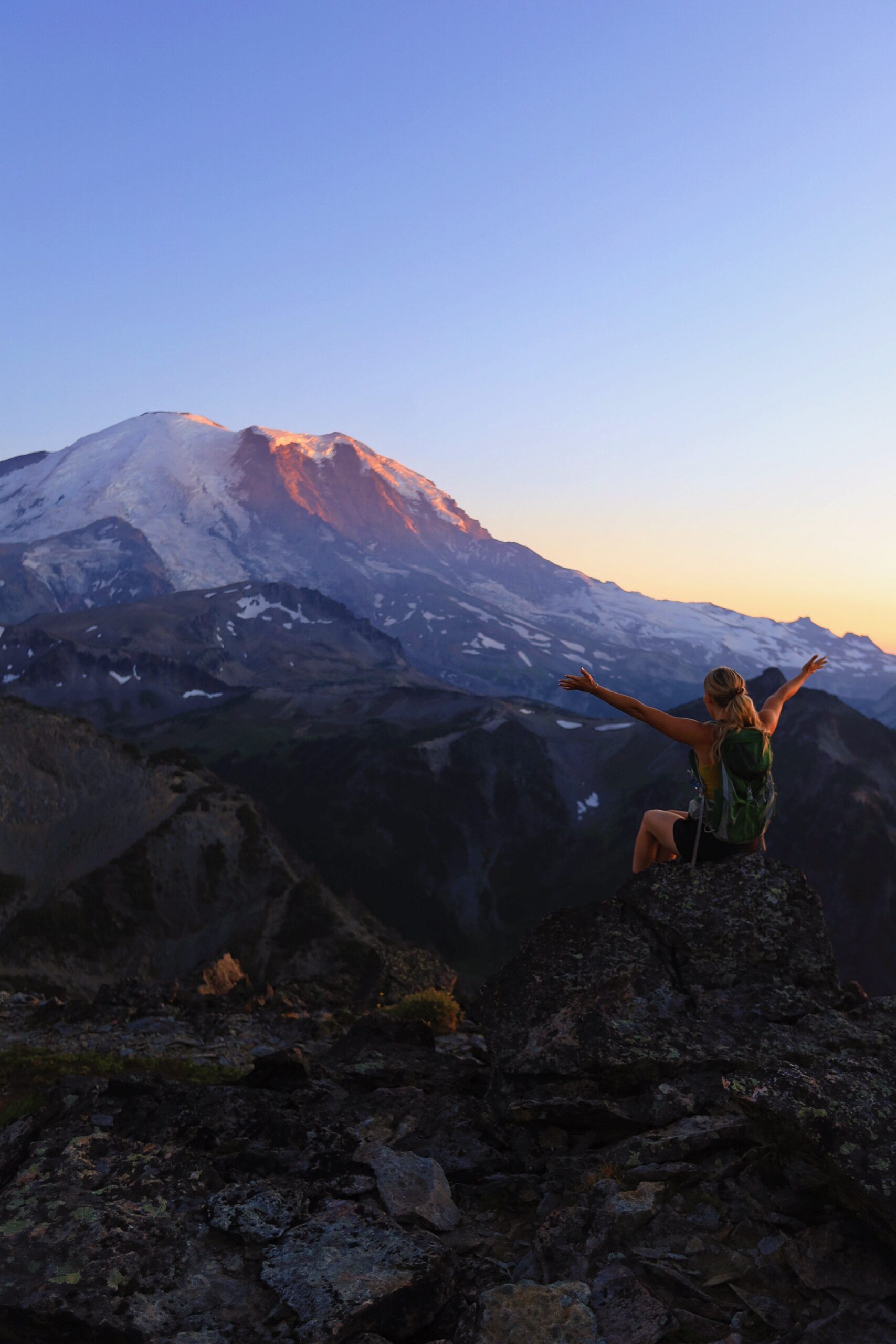 mount rainier with girl in the foreground enjoying golden hour